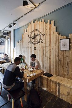 two people sitting at a table in front of a wall made out of wooden planks