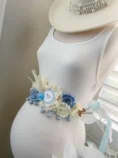 a white dress with blue flowers and pearls on the collar is displayed in front of a window