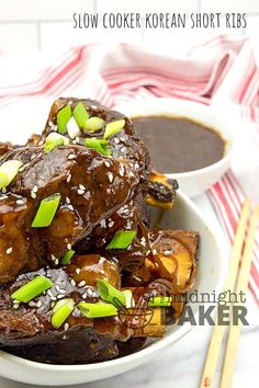 a white bowl filled with meat covered in sauce and topped with green onions, sesame seeds