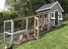 a chicken coop in the grass next to a fence