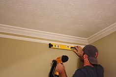 a man is working on the ceiling with a pair of drillers and a screwdriver