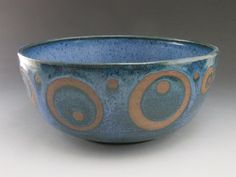 a blue and orange bowl with circles on the inside is sitting on a white surface