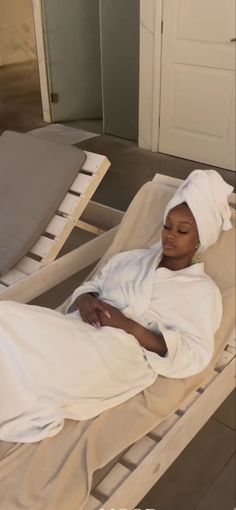 a woman laying on top of a bed covered in a white blanket next to a door