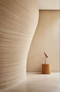 a wooden sculpture sitting in front of a wall next to a lamp on top of a table