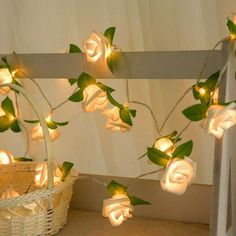 white roses with green leaves are lit up on the wall next to a wicker basket