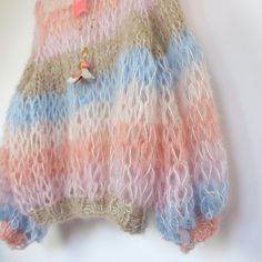 a colorful sweater hanging on a wall with a tag attached to the top of it