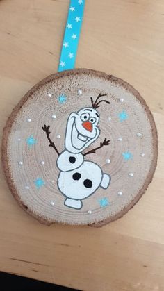 a wooden ornament with a cartoon character painted on it's face and blue ribbon