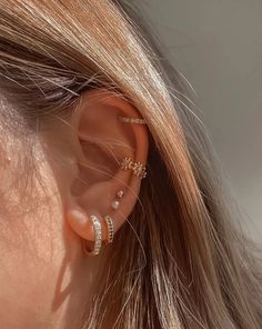 a woman wearing ear piercings with two small gold stars on the top of her ear