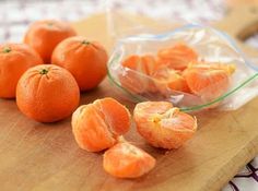 peeled oranges sitting on a cutting board next to a plastic bag