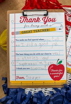 a thank you note with an apple on it and blue streamers next to it