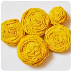 four yellow rolled flowers sitting on top of each other