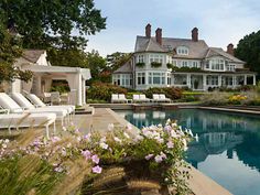 a large house sitting next to a swimming pool with chaise lounges around it