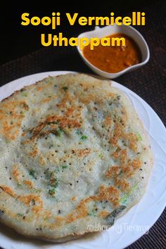 a white plate topped with food next to a bowl of dipping sauce on top of a table