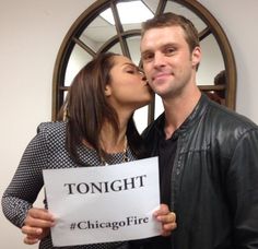 a man and woman kissing each other while holding a sign that says tonight chicago fire