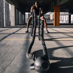 two men doing pull ups on ropes in the middle of an empty parking garage area