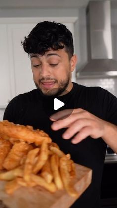 a man holding a wooden cutting board filled with fried food