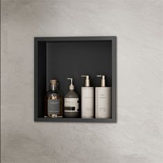 a bathroom shelf with soap, lotion and hand sanitizers on it in front of a white wall