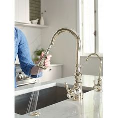 a woman is washing her hands under the kitchen sink faucet with water running from it