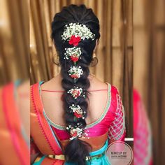 a woman with long black hair wearing a flowered headpiece and braid in her hair