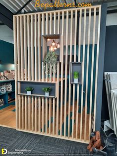 a room divider made out of wooden slats with plants in the corner and shelves on either side