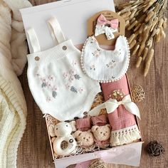 a box filled with baby items on top of a wooden floor next to dried flowers