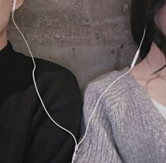 two people wearing headphones are standing next to each other in front of a concrete wall