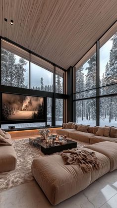 a living room filled with lots of furniture and large windows overlooking the snow covered trees