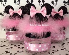 three minnie mouse cupcakes with pink bows and feathers in them on a table