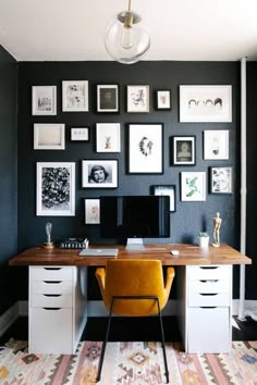 a home office with black walls and pictures on the wall, including a yellow chair