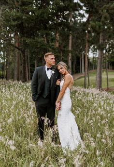 a bride and groom standing in tall grass