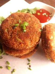 three fried food items sitting on top of a white plate next to ketchup