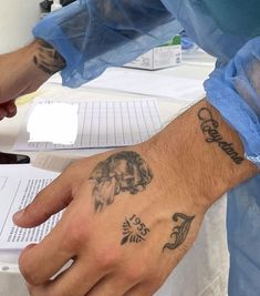 a person with a tattoo on their arm and hand next to an open book in front of them