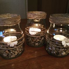 three mason jars filled with rocks and lit candles