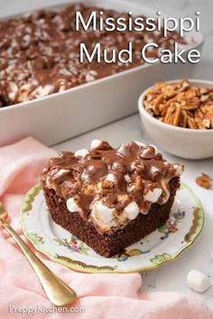 a piece of chocolate mississippi mud cake on a plate next to a bowl of marshmallows