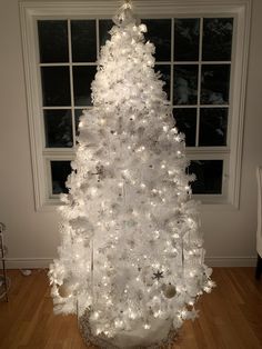 a white christmas tree in front of a window