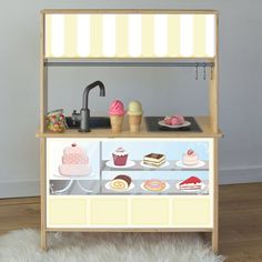 an ice cream stand with cakes and cupcakes on it's display shelf