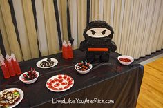 a table topped with lots of desserts and drinks next to a curtained window