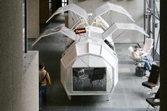 people are sitting and standing around in an office building with large sculptures on the walls