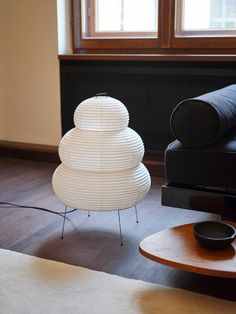 a living room with a black couch and white lamp