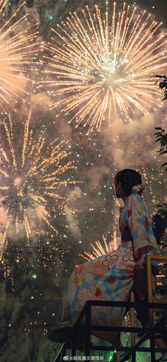 a woman sitting on top of a chair next to a firework display in the sky