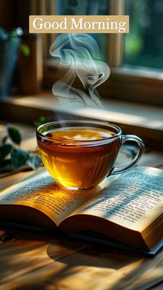 a cup of tea sitting on top of an open book with the words good morning