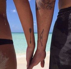 two people holding hands with tattoos on them