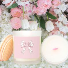 a candle and some flowers on a white surface with pink candles in front of it