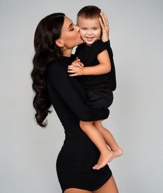 a woman is holding a small child in her arms and kissing the baby's cheek