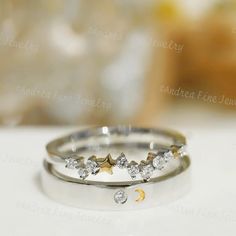 two wedding rings with stars and moon designs on the side, sitting on a table