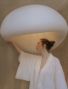 a woman is holding up a large white object