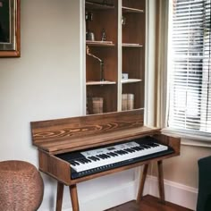 a piano sitting in front of a window next to a chair