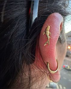 a close up of a persons ear with a lizard tattoo on it's side