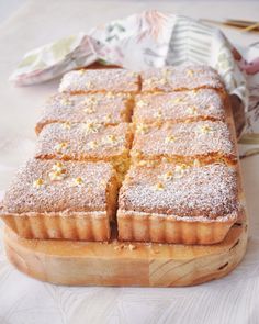 a wooden cutting board topped with a sliced cake covered in powdered sugar on top of a table