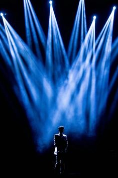 a man standing in front of three blue spotlights